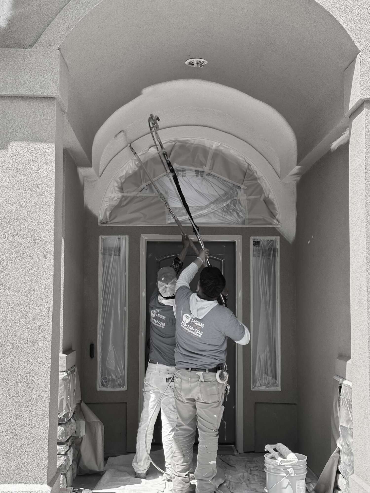 Two painters painting the ceiling.